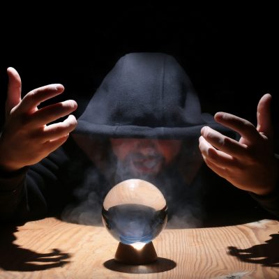 man in a black hood with cristal ball summon evil